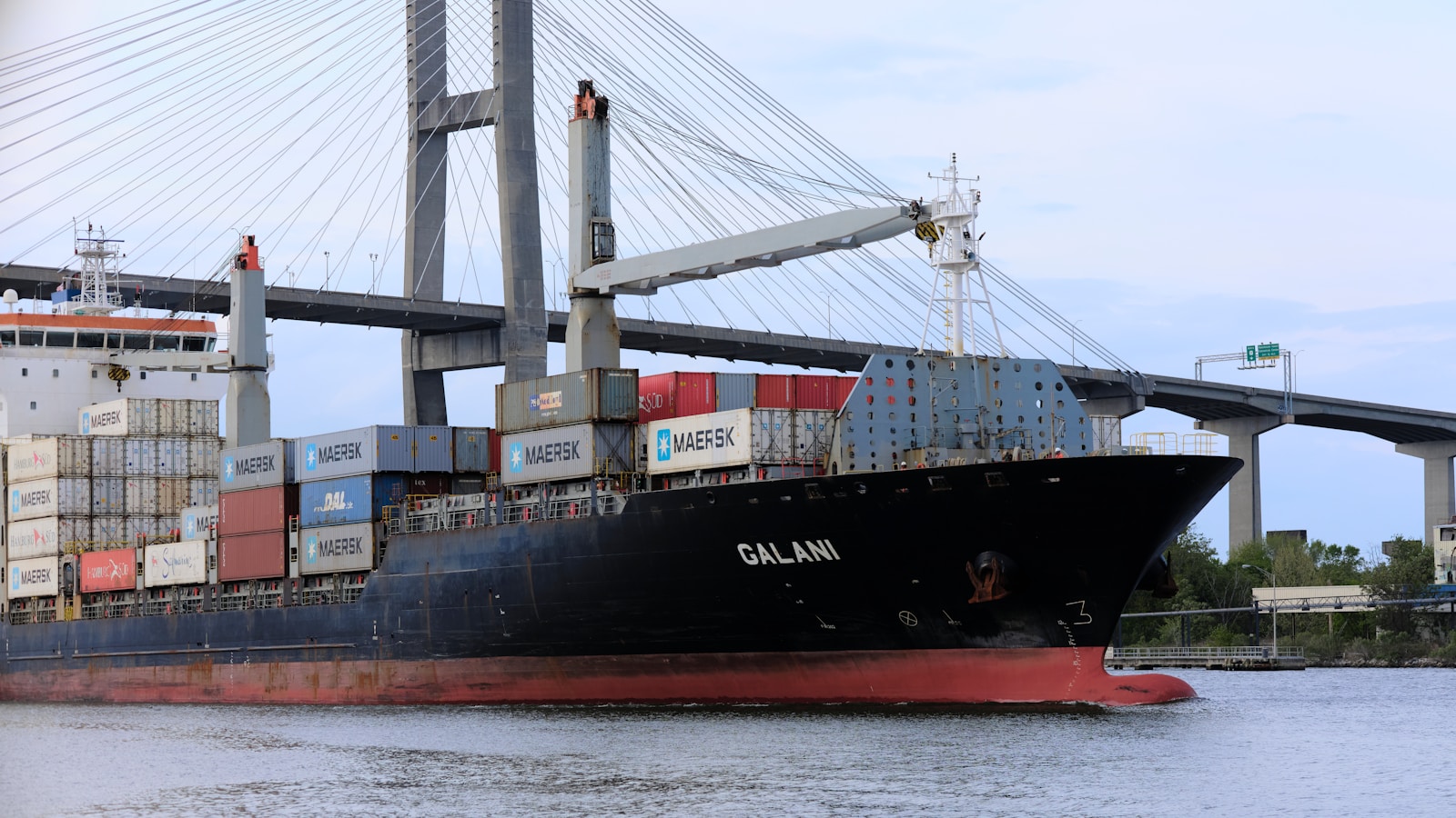 a large cargo ship in the water under a bridge