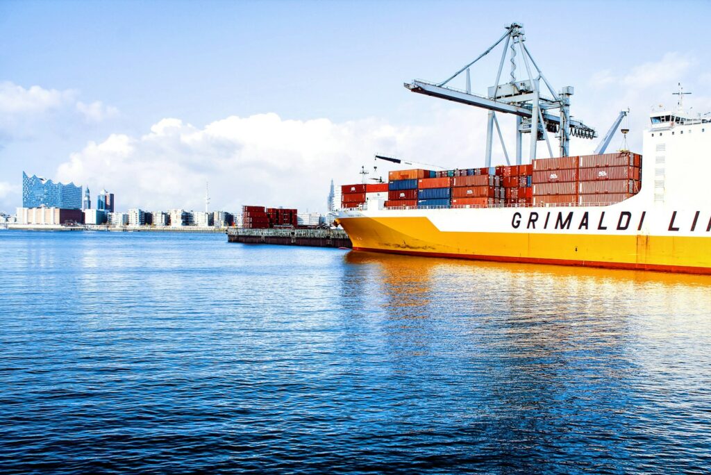 white and orange cargo ship with metal lifting equipment